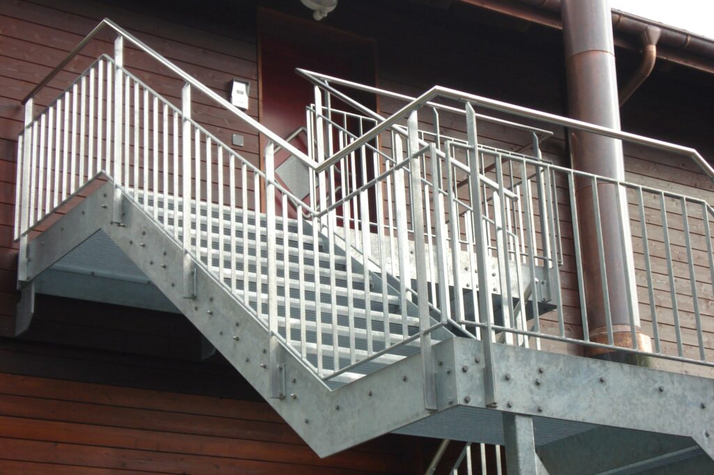 Treppe mit Gitterrosttritten, verzinkten Stakettengeländer und Chromstahlhandlauf